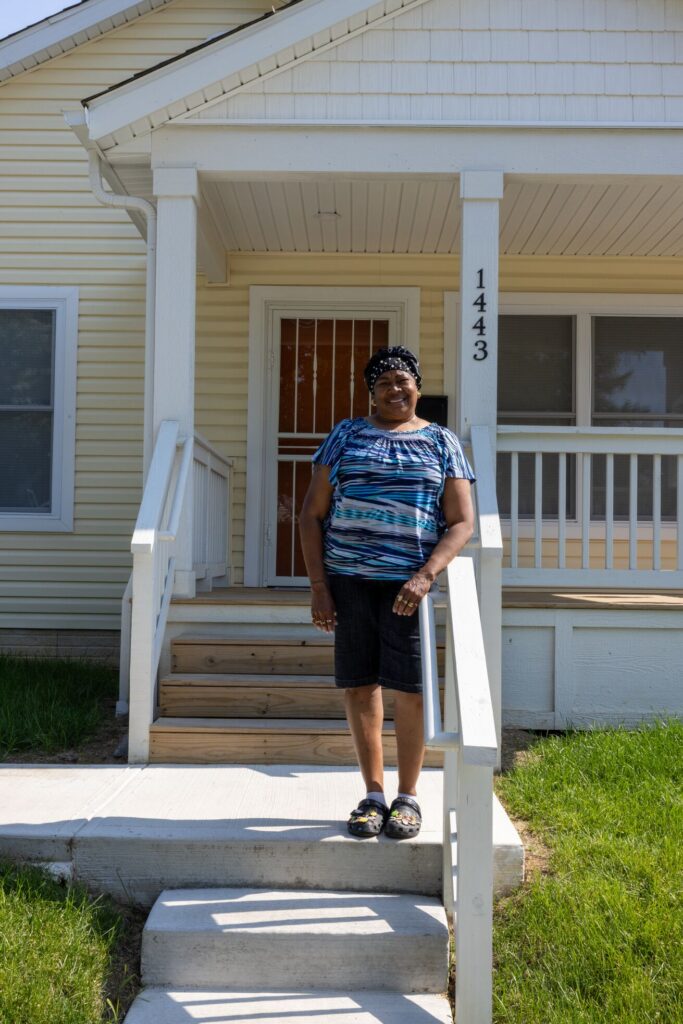 women standing on the porch of her yellow house