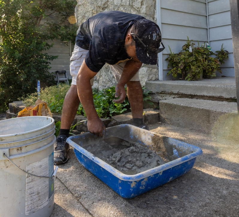man mixing concrete in a bin for repairing a front porch